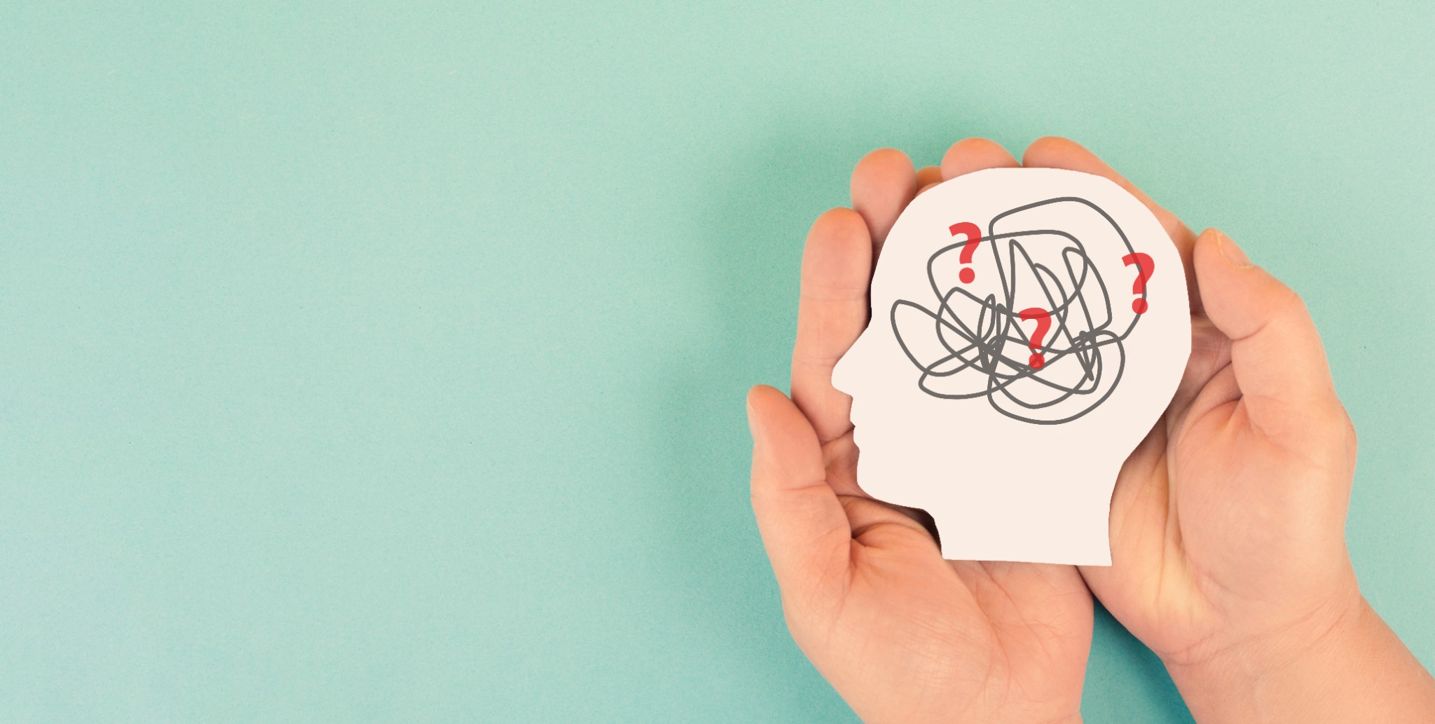 Hands holding a head-shaped card illustrating cognitive questions
